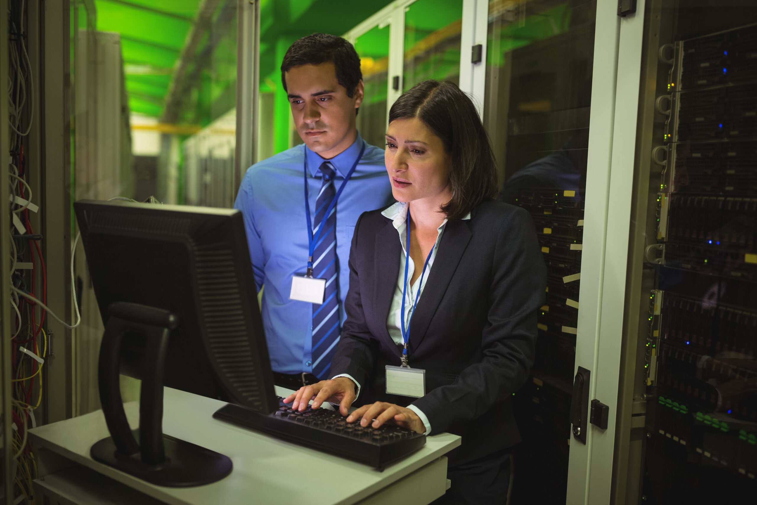 Technicians working on personal computer while analyzing server in server room