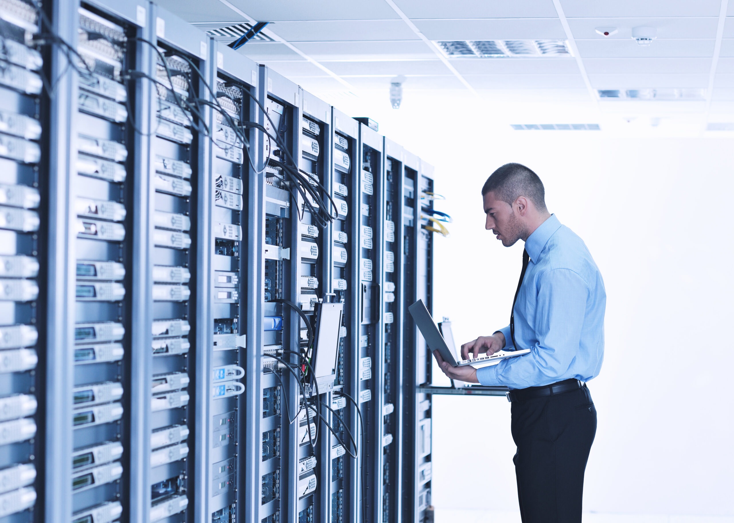 Young engeneer business man with thin modern aluminium laptop in network server room